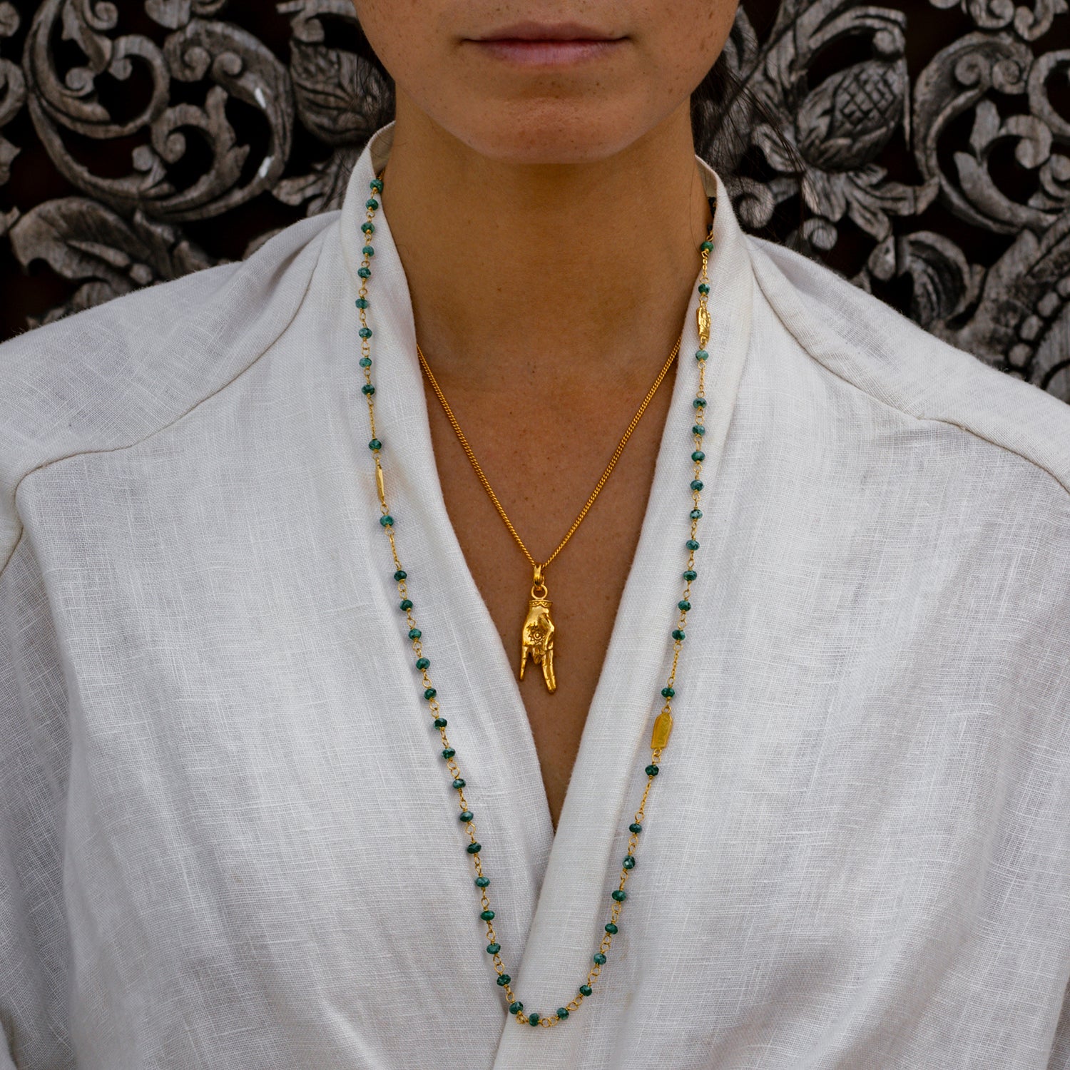 Yoga Teacher Steffi trägt eine Halskette aus hochwertig vergoldetem Sterling Silber mit Buddha-Emblemen und Jadeperlen
