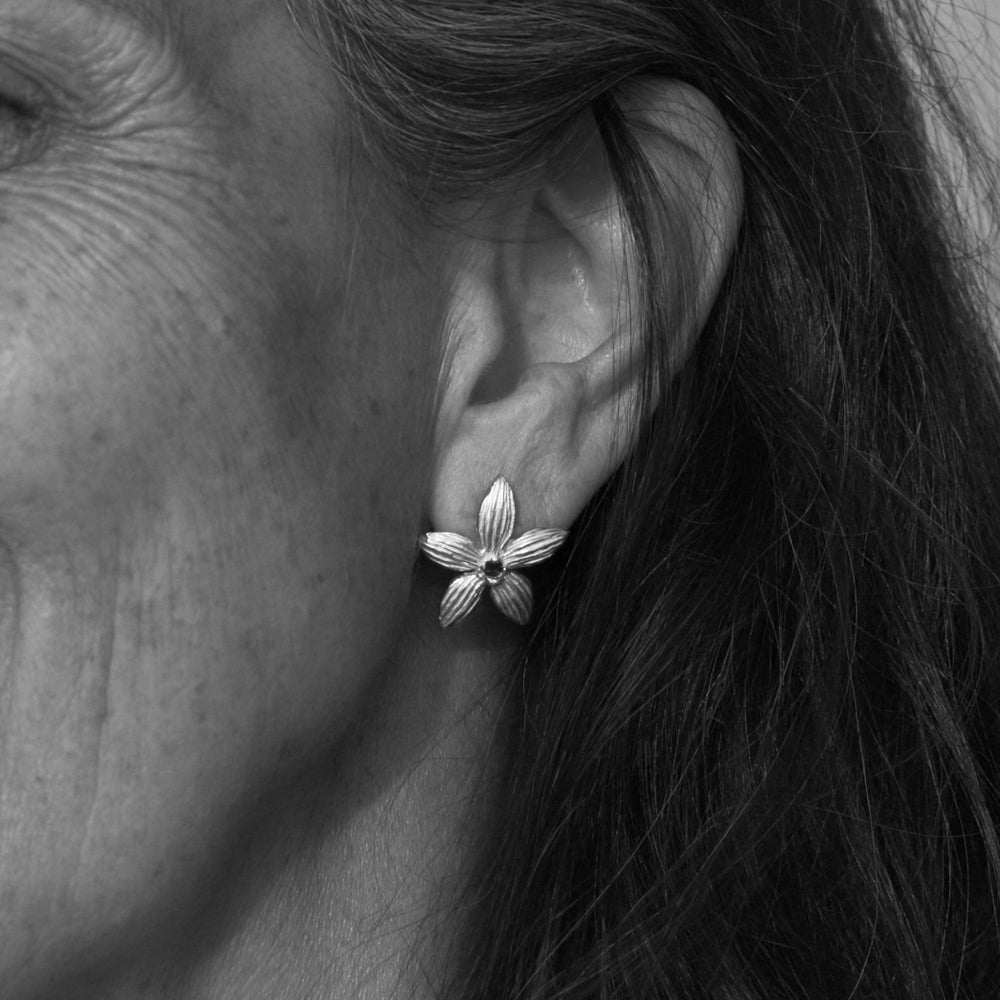 Cora trägt die silbernen Blue-China-Orchid-Ohrstecker mit schwarzem Saphir von ETERNAL BLISS Heilblüte