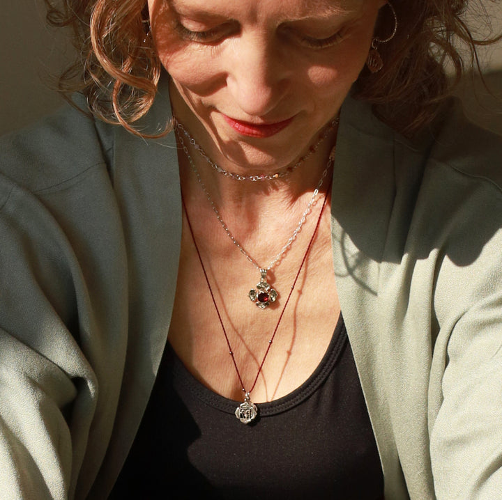 Elena Fröhlich, Yoga Lehrerin in Berlin, trägt den kleinen Wurzel-Chakra-Anhänger aus Sterling Silber an einer granatroten Halskordel