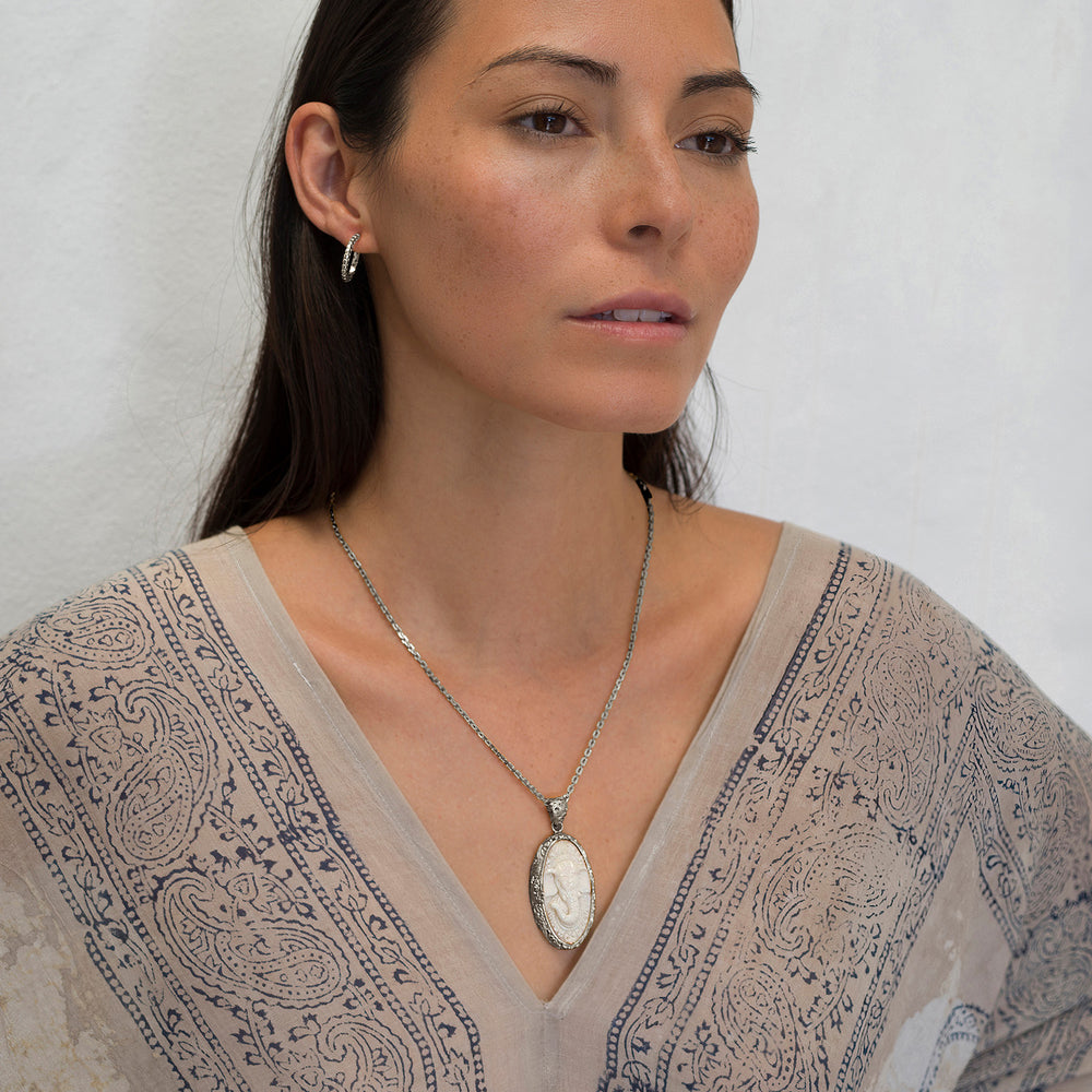 Die Yogalehrerin Steffi, in weißem Gewand, trägt einen hochwertigen Ganesha Anhänger mit geschnitztem Einleger und reich verziertem Rahmen aus Sterling Silber an einer kräftigen Halskette von ETERNAL BLISS - Spiritueller Schmuck