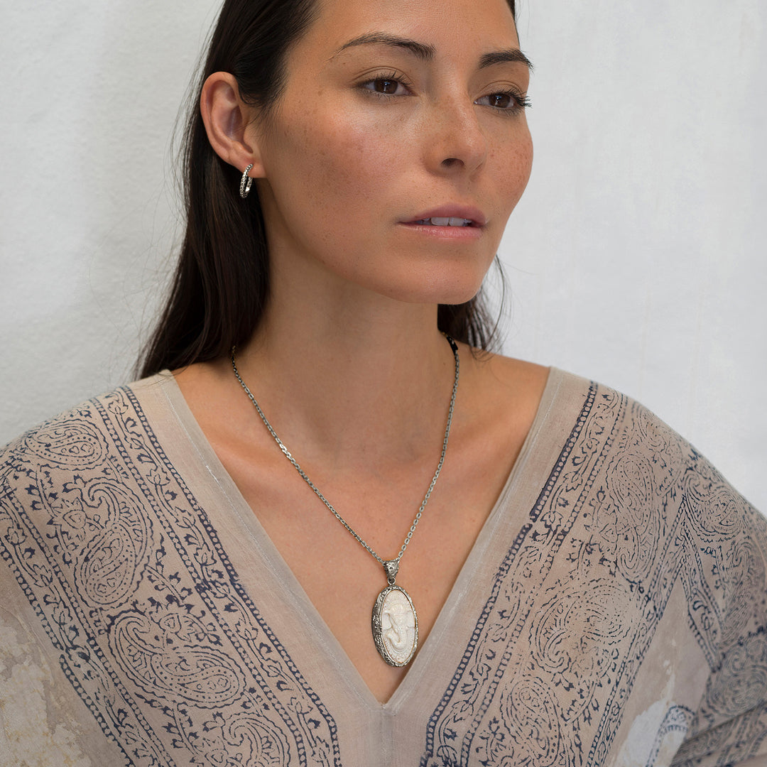 Die Yogalehrerin Steffi, in weißem Gewand, trägt einen hochwertigen Ganesha Anhänger mit geschnitztem Einleger und reich verziertem Rahmen aus Sterling Silber an einer kräftigen Halskette von ETERNAL BLISS - Spiritueller Schmuck