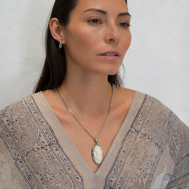 Die Yogalehrerin Steffi, in weißem Gewand, trägt einen hochwertigen Ganesha Anhänger mit geschnitztem Einleger und reich verziertem Rahmen aus Sterling Silber an einer kräftigen Halskette von ETERNAL BLISS - Spiritueller Schmuck